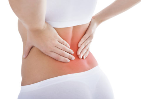 Woman suffering from lower back pain in white